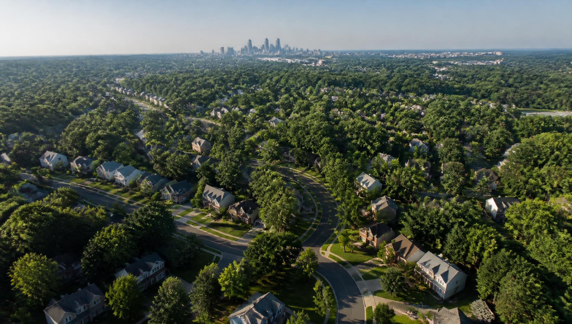 Aerial view of a wooded south Charlotte neighborhood with the Uptown skyline in the distance
