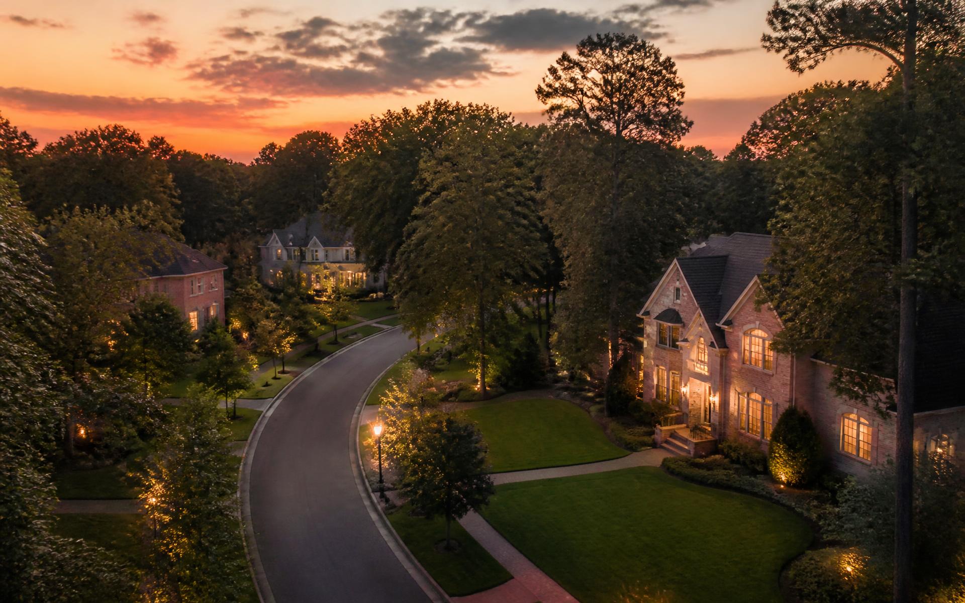 Custom brick homes along a tree-lined street in Montibello, south Charlotte, at dusk